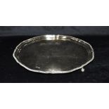 A SILVER SALVER the salver with ribbed pie crust border on three ball feet, hallmarked for London