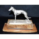 A PLATED FIGURE OF A STANDING GREYHOUND On a shaped wooden plinth base, 22.5cm high, 31.5cm wide.