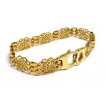 A 9CT GOLD BRACELET The bracelet of open work design in alternating fancy link panels with a large