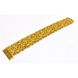 A 9CT GOLD BRACELET IN STRAP DESIGN The wide band bracelet comprising of hinged panels in abstract