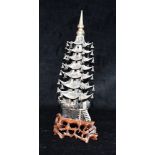 A CHINESE WHITE METAL MODEL OF A PAGODA each of the seven tiers with suspended bells, on carved