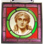 A STAINED GLASS PANEL the central roundel with a portrait of a young woman, overall 36.5cm x 36.5cm.