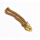 A 9CT ROSE GOLD CURB LINK BRACELET The bracelet fitted with a 9ct yellow gold heart padlock and