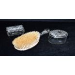 A SILVER BACKED HAIR BRUSH Together with two silver topped glass dressing table jars, the