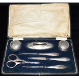 A HALLMARKED SILVER SEVEN PIECE MANICURE SET cased, nail buff, two small silver lidded glass jars,
