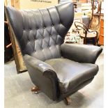 A G-PLAN 'SIXTY-TWO' STYLE RETRO SWIVEL ARMCHAIR with black vinyl upholstery, on four prong wooden