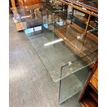 A LAMINATED GLASS DESK the rectangular top 180cm x 79cm, on shaped supports, 76cm high Condition