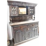 AN EDWARDIAN OAK DRESSER the upper section with carved frieze above mirror flanked by cushion shaped