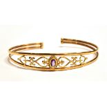A MARKED 375 OPENWORK HEART TORQUE BANGLE centrally set with a purple almandine flanked each side
