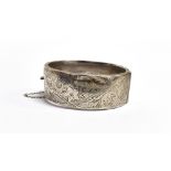 A VINTAGE SILVER BANGLE the half patterned wide band bangle, with safety chain, hallmarked for