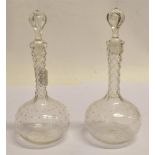 A PAIR OF GLASS DECANTERS AND STOPPERS with facet cut stems, the bodies and stopper cut star