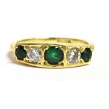 AN EMERALD AND DIAMOND DRESS RING the ring set with three graduated round cut emeralds,