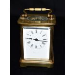 A BRASS CASED CARRIAGE CLOCK the enamel dial with Roman numerals, 12cm high with carrying handle