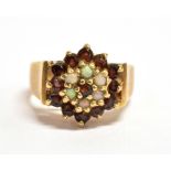 A 9CT GOLD, OPAL AND GARNET GLASS FLOWER HEAD RING The flower head measuring 1.2cm x 1.2cm, the