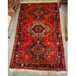 A RED GROUND RUG with triple medallion, 127cm x 215cm