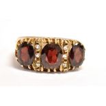 A 9CT GOLD, GARNET THREE STONE DRESS RING The faceted oval garnets measuring approx. 0.7cm X 0.5cm