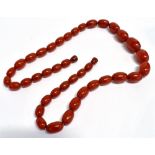 A VINTAGE CHERRY AMBER COLOURED BEAD NECKLACE the necklace of graduated oval vintage plastic