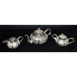 A CHINESE WHITE METAL THREE PIECE TEA SET The set comprising of a tea pot, lidded creamery and a