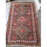 A RED GROUND RUG with triple pole medallion, 120cm x 193cm