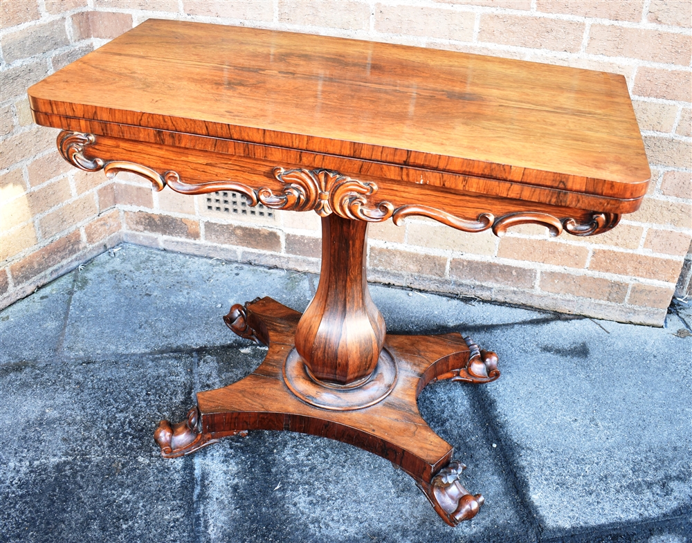 AN EARLY VICTORIAN ROSEWOOD CARD TABLE with carved decoration, on octagonal inverted baluster pillar