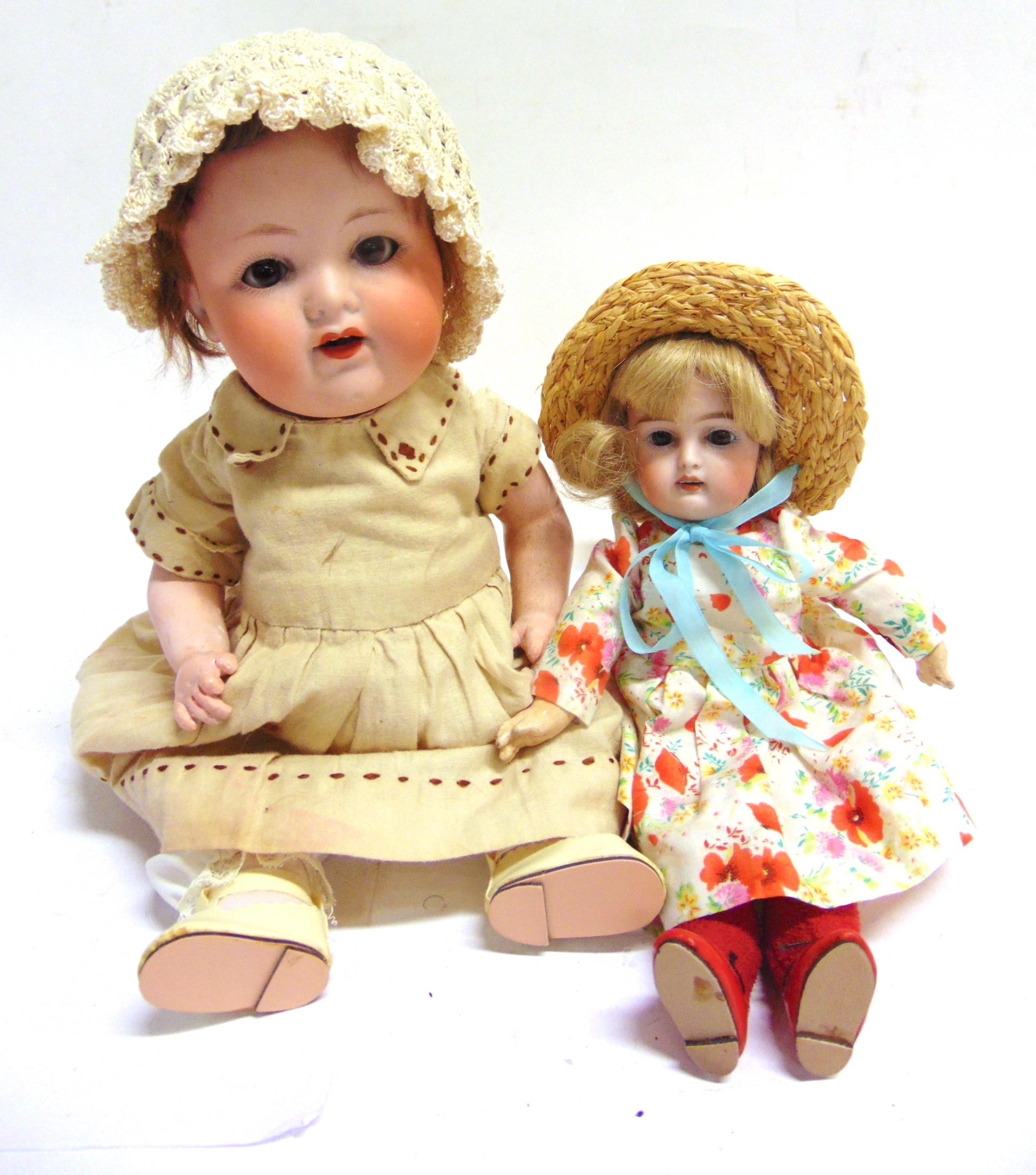 TWO BISQUE DOLLS comprising an Armand Marseille bisque socket head doll, with a cropped brown wig,