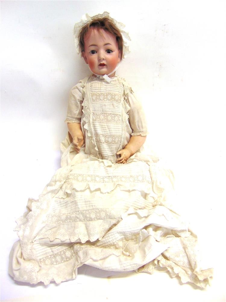 A KONIG & WERNICKE BISQUE SOCKET HEAD DOLL with a cropped brown wig, sleeping brown glass eyes,