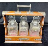 A VICTORIAN EP MOUNTED THREE DECANTER OAK TANTALUS with silver plated wine labels for 'PORT', '