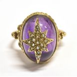 A 9CT GOLD SEED PEARL STAR SET BOULE RING The ring set with a boule of purple garnet glass with a