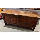 AN OAK COFFER the lid with chip carved decoration, the panelled front with carved decoration,