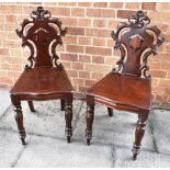 A PAIR OF CARVED MAHOGANY HALL CHAIRS with serpentine front seats on octagonal baluster supports