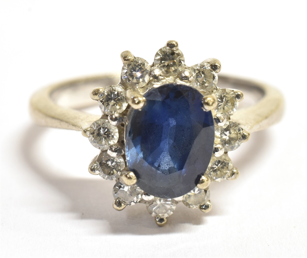 A STAMPED 750 DIAMOND AND SAPPHIRE CLUSTER RING the facetted oval blue sapphire measuring 9 x 6mm