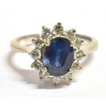 A STAMPED 750 DIAMOND AND SAPPHIRE CLUSTER RING the facetted oval blue sapphire measuring 9 x 6mm