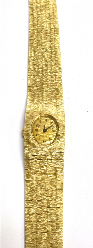 A 9CT GOLD LADIES WRISTWATCH The oval signed dial on an integral textured brick strap, the clasp