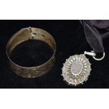 A RETRO SILVER BANGLE together with a Victorian white metal locket, the silver bangle fashioned as a