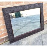 A RECTANGULAR WALL MIRROR the hardwood framed carved with trailing vine leaves, 64.5cm x 86cm