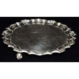 A FOOTED SILVER SALVER A George V circular silver salver with raised pie crust border on three feet,