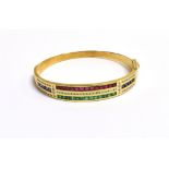 A CALIBRE CUT RUBY, EMERALD, SAPPHIRE AND ROUND CUT DIAMOND BANGLE the bangle half set with twelve