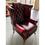 A RED LEATHER BUTTON UPHOLSTERED WING ARMCHAIR with scroll arms, on cabriole supports Condition