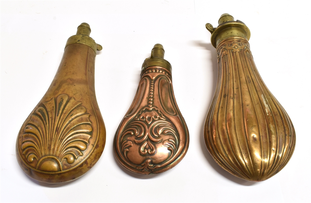 TWO BRASS POWDER FLASKS of stylized design and a small copper flask, all with brass mounts, the