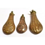 TWO BRASS POWDER FLASKS of stylized design and a small copper flask, all with brass mounts, the