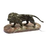 A CAST FIGURE OF A STANDING GROWLING LION on an oval flecked marble base (detached) Height 13cm (