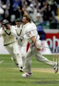 Shane Warne (Australia) hand signed 8 by 12in. action photograph, taking his 700th Test Wicket at