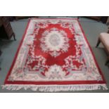 A red ground oriental style rug with floral central medallion and matching borders 277cm long x