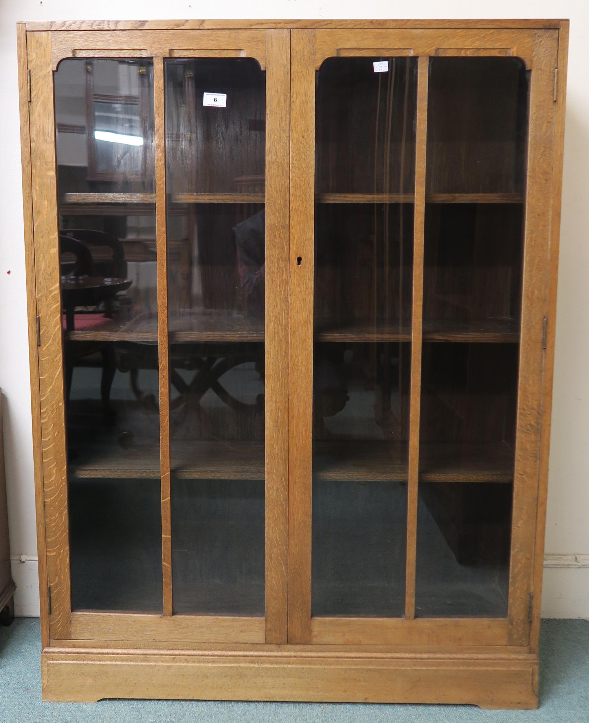 An early 20th century oak art deco two door glazed bookcase three internal shelves 112cm high x 92cm