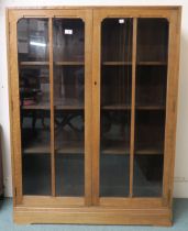 An early 20th century oak art deco two door glazed bookcase three internal shelves 112cm high x 92cm