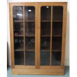 An early 20th century oak art deco two door glazed bookcase three internal shelves 112cm high x 92cm