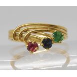 A bright yellow metal three strand design ring set with ruby, sapphire and emerald, size L, weight