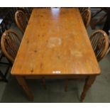 A 20th century pine kitchen table 77cm high x 140cm long x 81cm deep and four beech wheelback dining
