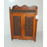 An oak smokers cabinet with carved hinged doors, turned tobacco box and pipes etc Condition