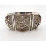 A white metal Indian hand repoussed and engraved  bangle depicting Gods and Goddesses Condition